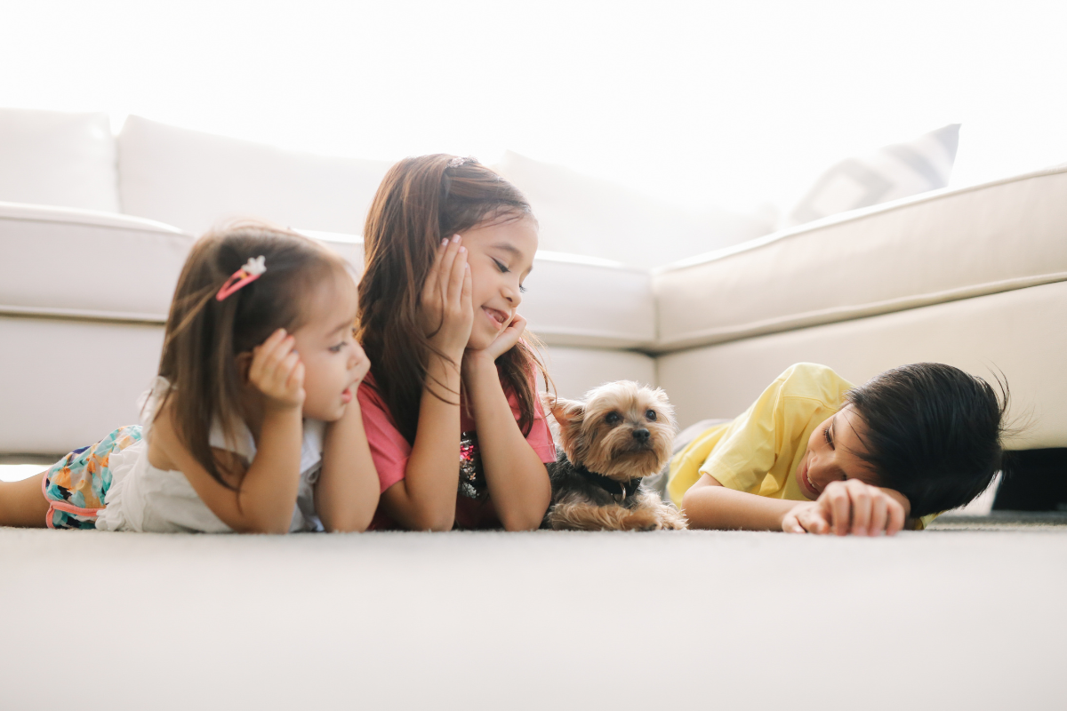Three children show their small dog playful love and care, embodying venus in Gemini zodiac traits