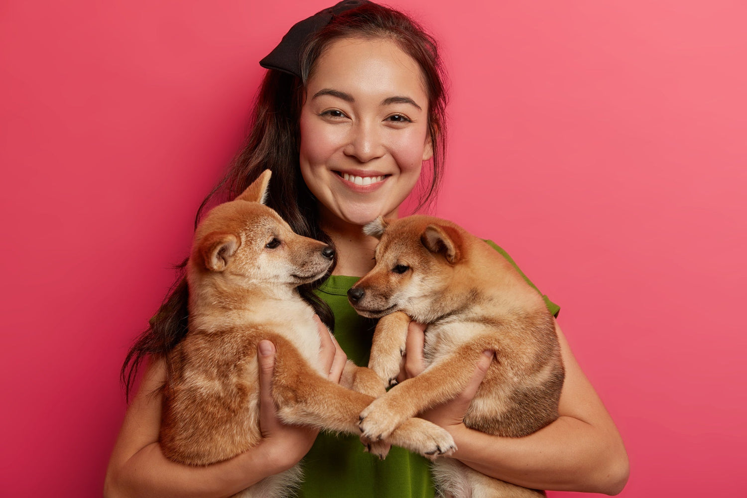 Asian woman poses with two small puppies