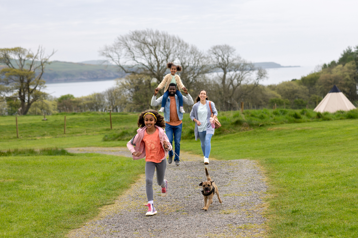 Young family with two kids exploring a park with their dog, enjoying Sagittarius pet care, mindful pet connection, and dog enrichment outdoors.