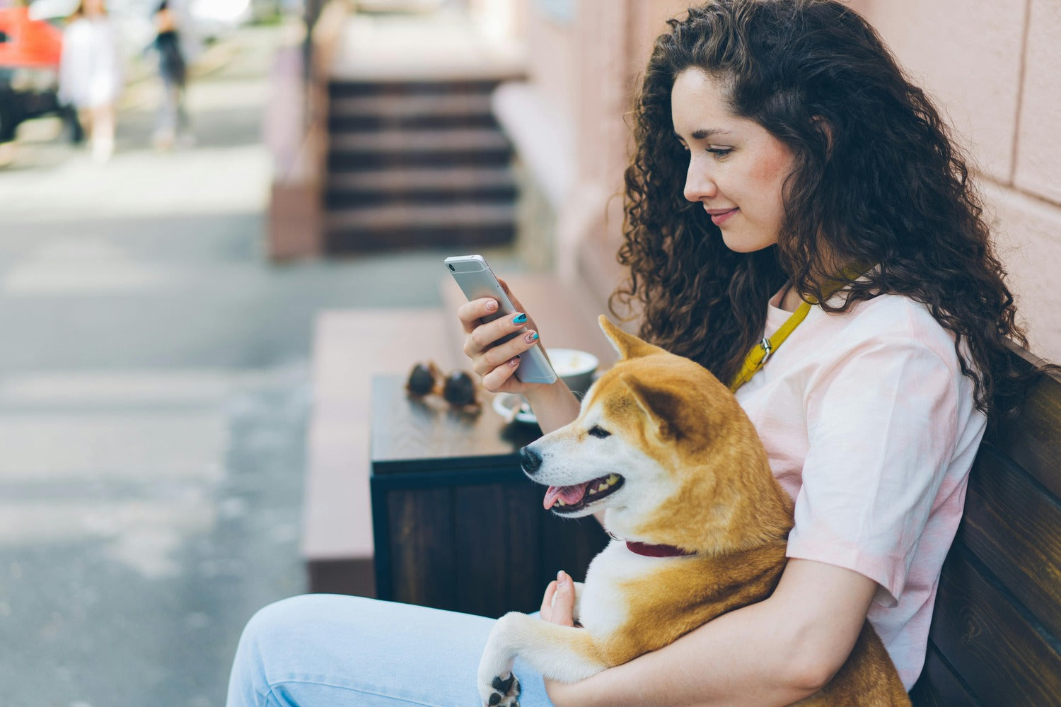A woman is using a phone with a dog beside her